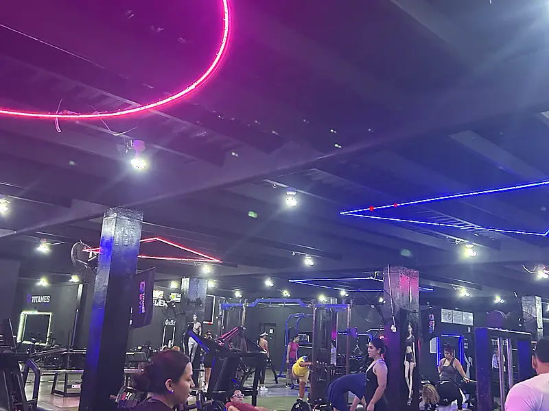 Ambiente de entrenamiento en Titanes Gym con iluminación de neón magenta